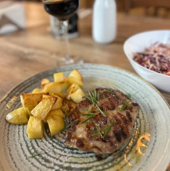 Preparat la grătar cu cartofi copți și salată, servit la Trattoria Al Gallo